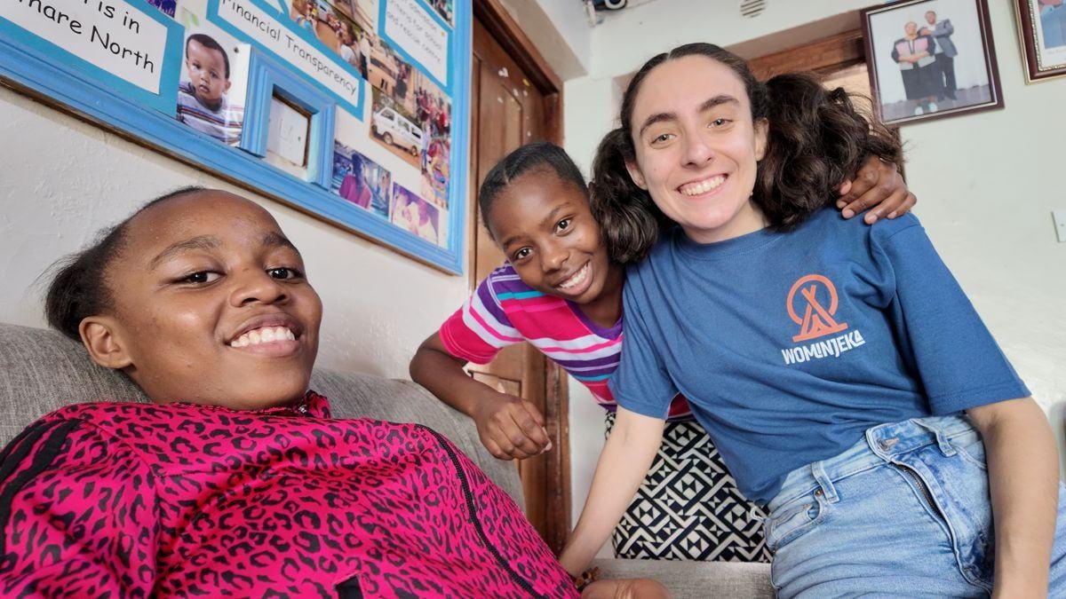 Two students and a Wominjeka volunteer, arms round each other, at the Mathare centre in Nairobi